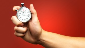 stock-photo-close-up-of-hand-holding-stopwatch-against-a-red-background-125650520